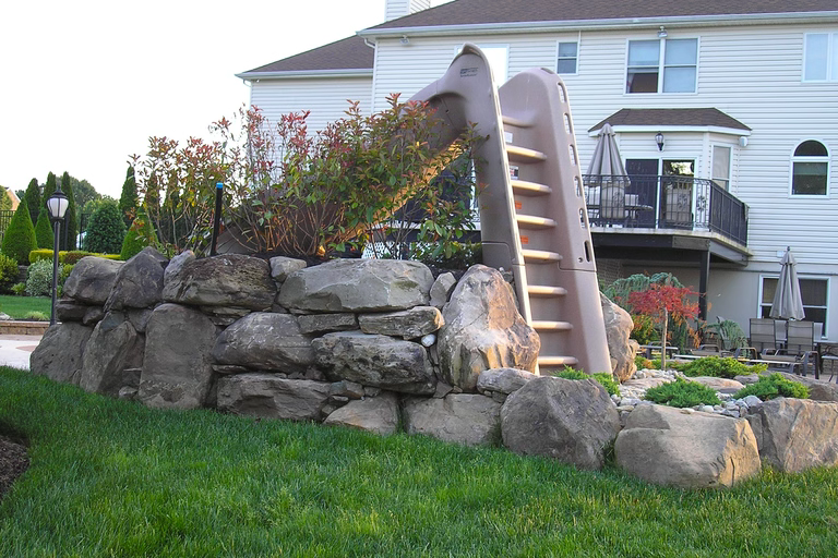 A large white house with a play structure in the middle of a lush green yard