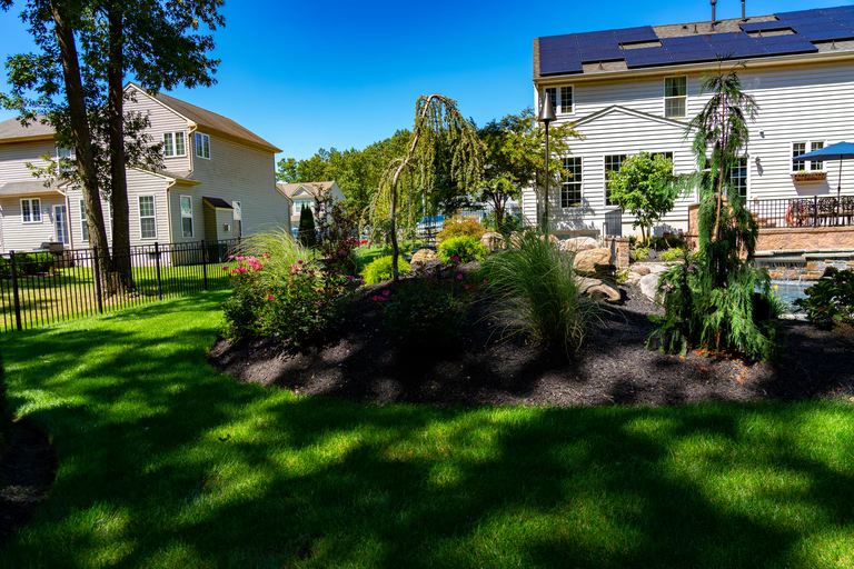 A well-maintained garden with a well-manicured lawn and a house with solar panels on the roof