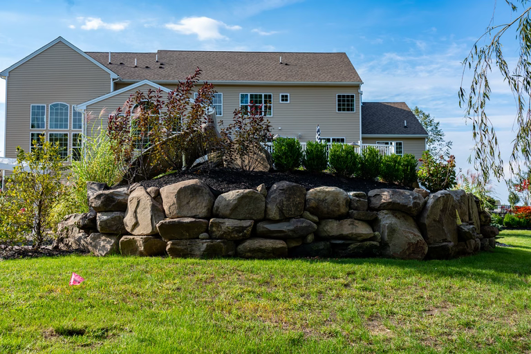 A large house with a large rock wall in front of it