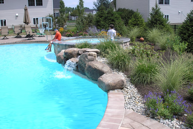 A swimming pool with a waterfall and landscaping around it