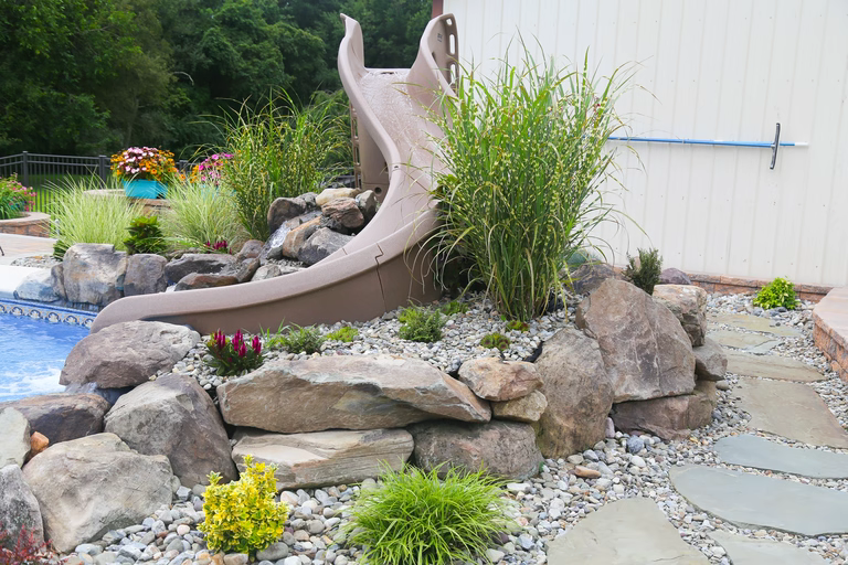 A rock garden with a water feature and a slide in the middle