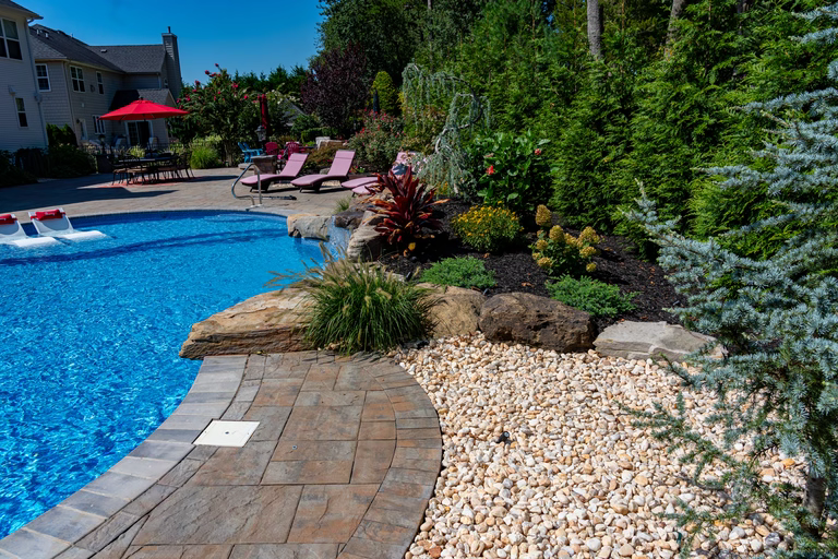 Natural stone boulder waterfall cascading into a pool surrounded by lush greenery