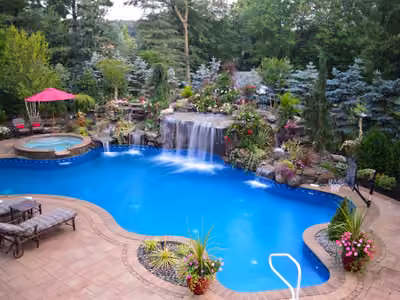Natural stone boulder waterfalls cascading into a freeform pool with lush floral landscaping