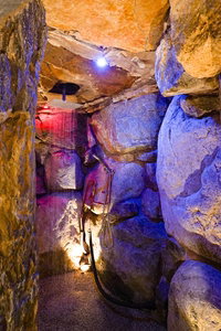 Sefinen R - Finksburg, MD - This custom installation features a natural stone waterfall cascading down rugged boulders, integrated with a built-in shower system. The space utilizes rough-hewn stone walls and a cave-like ambiance enhanced by blue LED lighting. The craftsmanship showcases seamless integration of water features with durable natural materials, creating a relaxing spa-like environment.