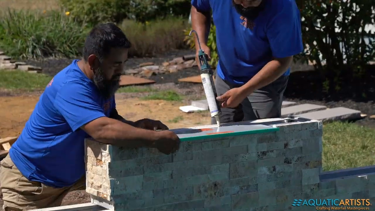 Aquatic Artists craftsmen setting stacked-stone veneer on a waterfall wall