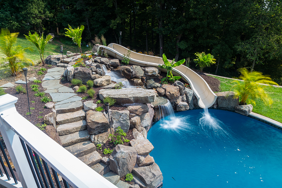 multi-tiered natural stone waterfall built into a hill with a stream that c...
