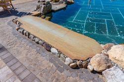 Day V - Manasquan, NJ - A stone walkway next to a swimming pool with rocks and pebbles