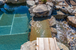 Day Z - Manasquan, NJ - A wooden boardwalk leading to a clear blue pool surrounded by rocks and pebbles