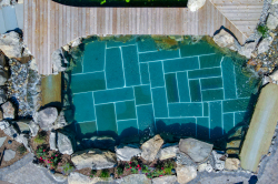 Day Z - Manasquan, NJ - A bird's eye view of a swimming pool surrounded by rocks and greenery
